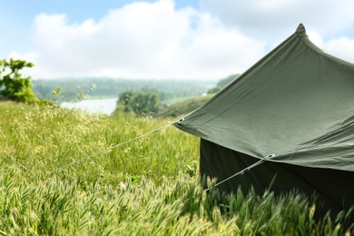 Photo of Camping tent in green field on sunny day. Space for text