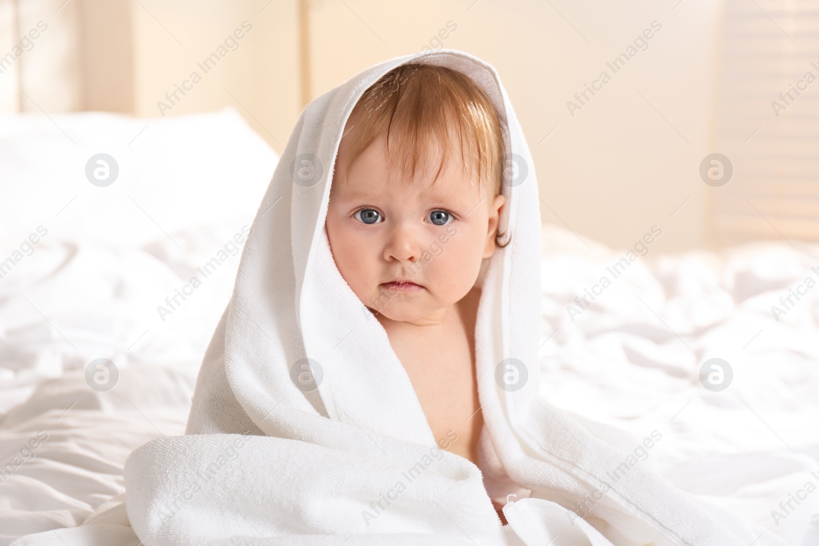 Photo of Cute little baby with soft towel on bed after bath