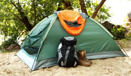 Camping tent with sleeping bag, boots and backpack on beach