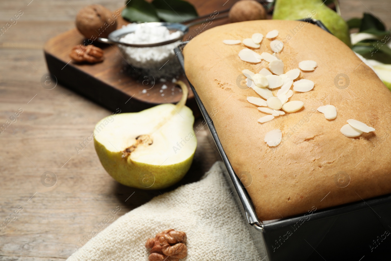 Photo of Tasty bread with almond flakes and pear on wooden table, closeup. Homemade cake