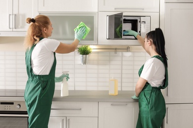 Photo of Professional janitors cleaning kitchen with supplies indoors