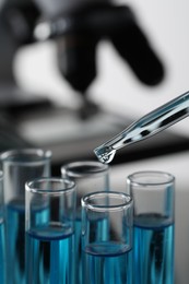 Dripping liquid from pipette into test tube in laboratory, closeup