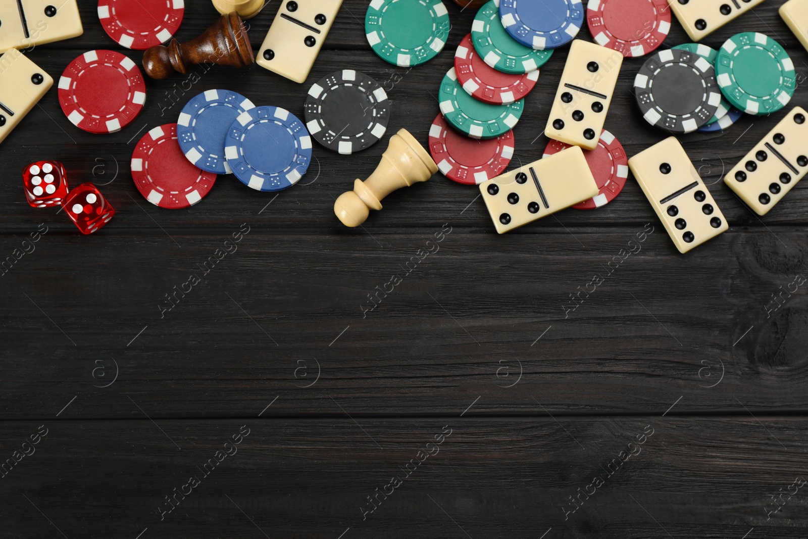 Photo of Elements of different board games on dark wooden table, flat lay. Space for text