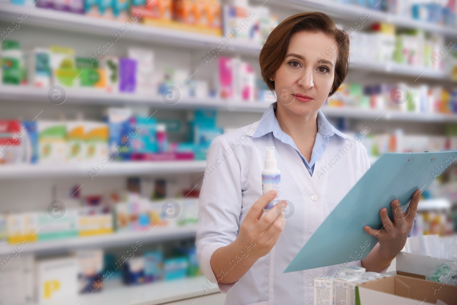 Photo of Professional pharmacist with clipboard and medicine in drugstore