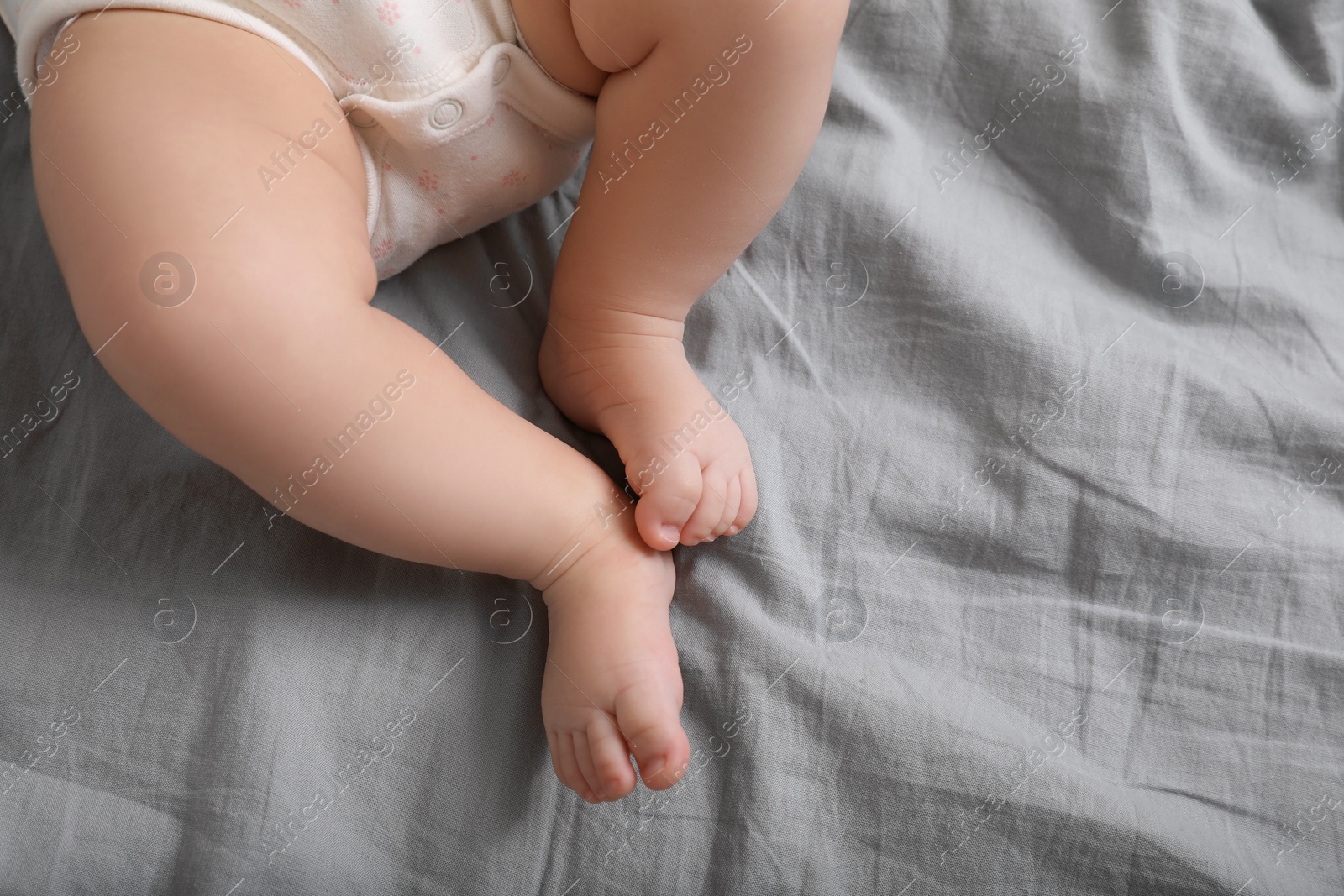 Photo of Little baby on bed, top view. Space for text