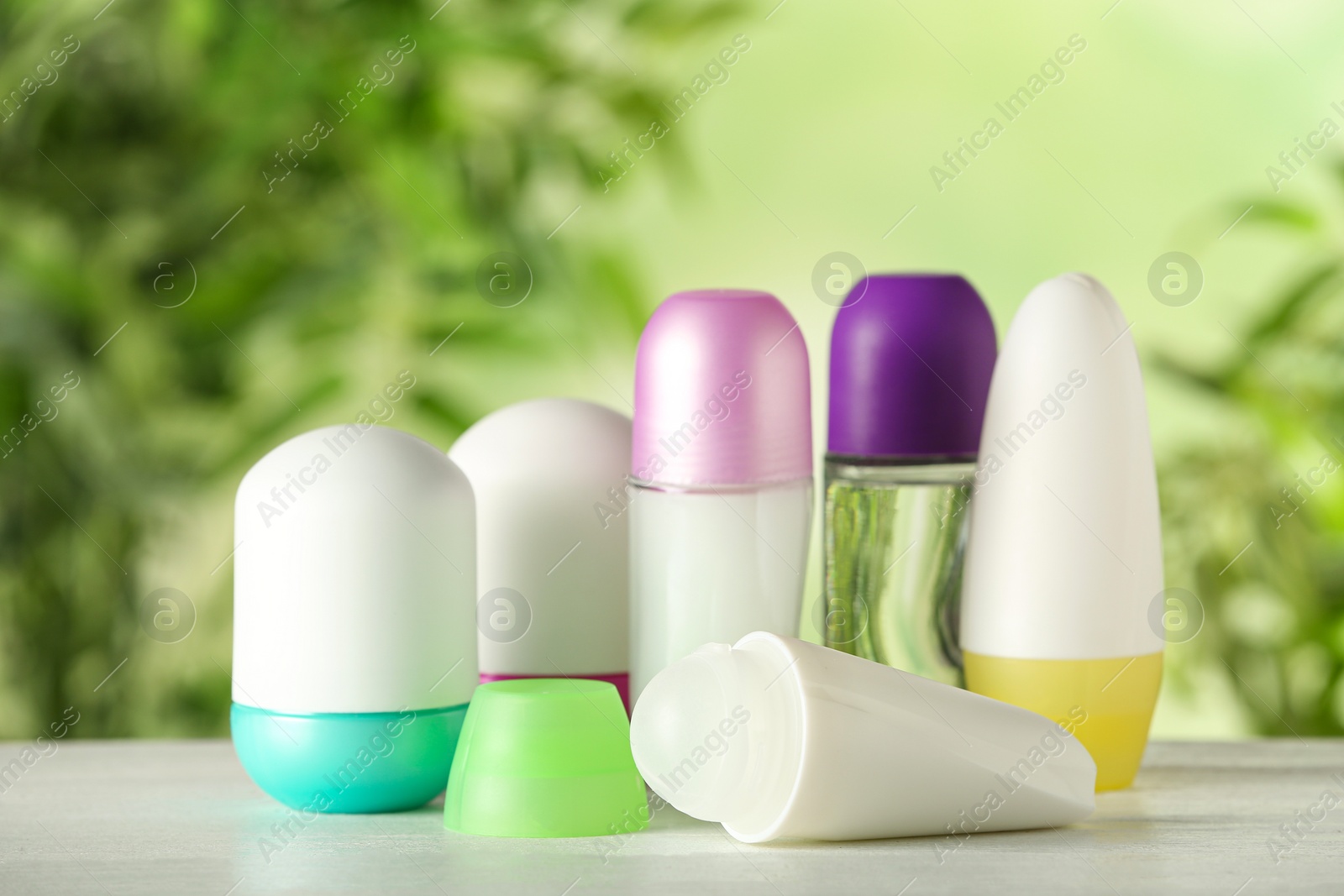 Photo of Different deodorants on white wooden table against blurred background