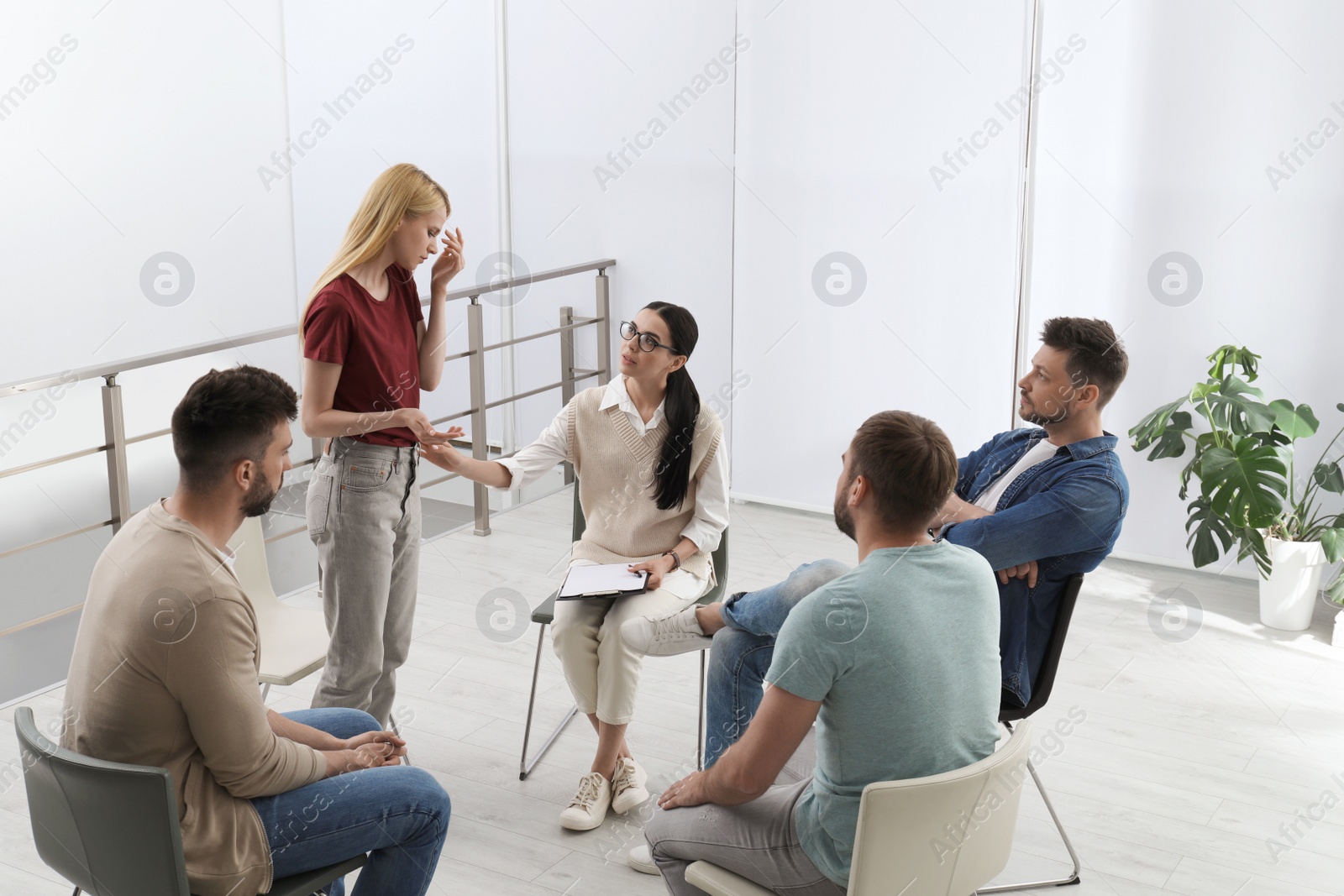 Photo of Psychotherapist working with group of drug addicted people at therapy session indoors