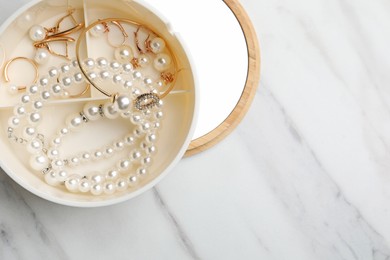 Photo of Stylish jewelry with pearls in box on white marble table, top view. Space for text