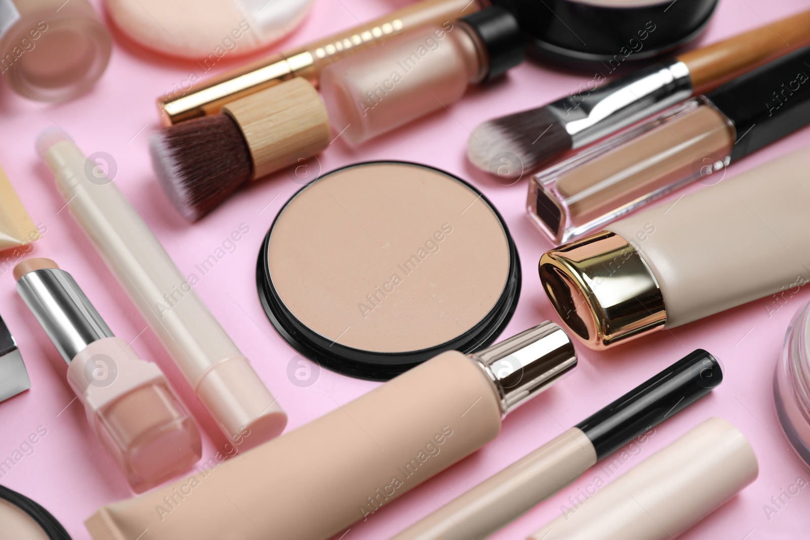 Photo of Face powder and other decorative cosmetic products on pink background