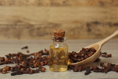 Essential oil and dry cloves on wooden table