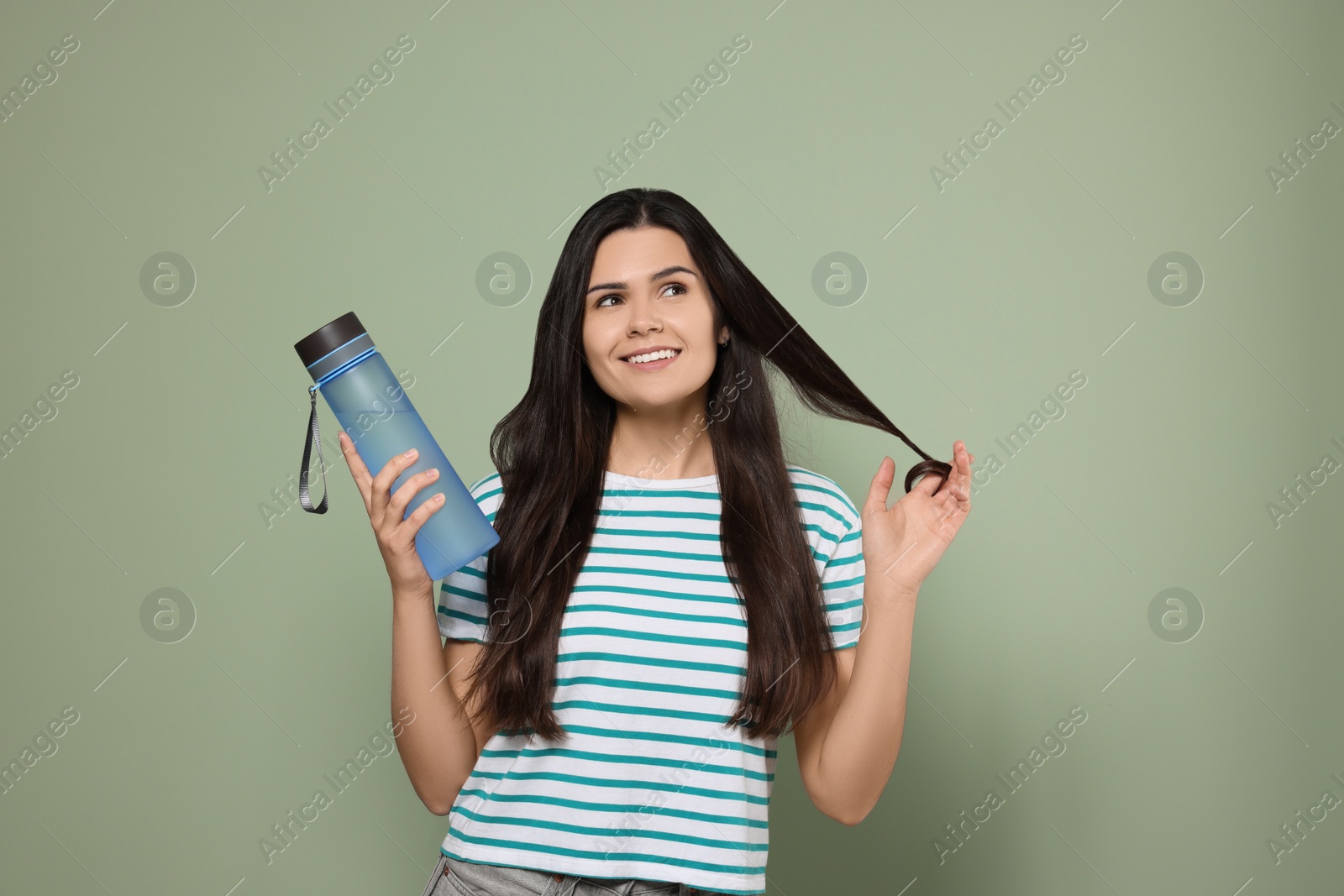 Photo of Young woman with bottle of water on green background