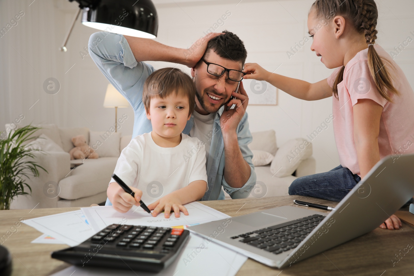 Photo of Overwhelmed man combining parenting and work at home