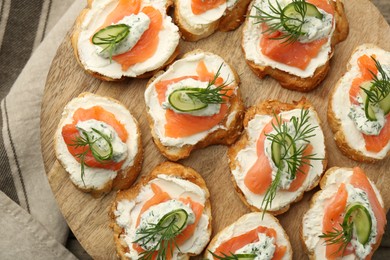 Tasty canapes with salmon, cucumber, cream cheese and dill on table, top view