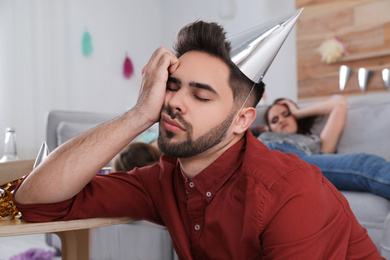Young man with festive cap sleeping at table after party