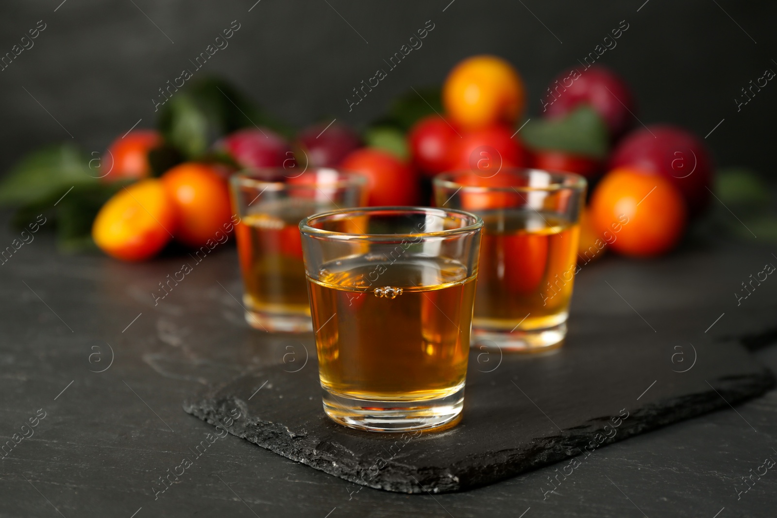 Photo of Delicious plum liquor on black table. Homemade strong alcoholic beverage