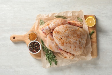 Board with raw spiced turkey and ingredients on light background, top view