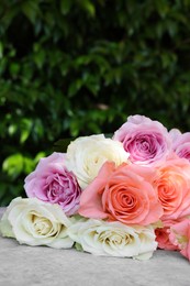 Photo of Beautiful bouquet of roses on light grey table outdoors, closeup