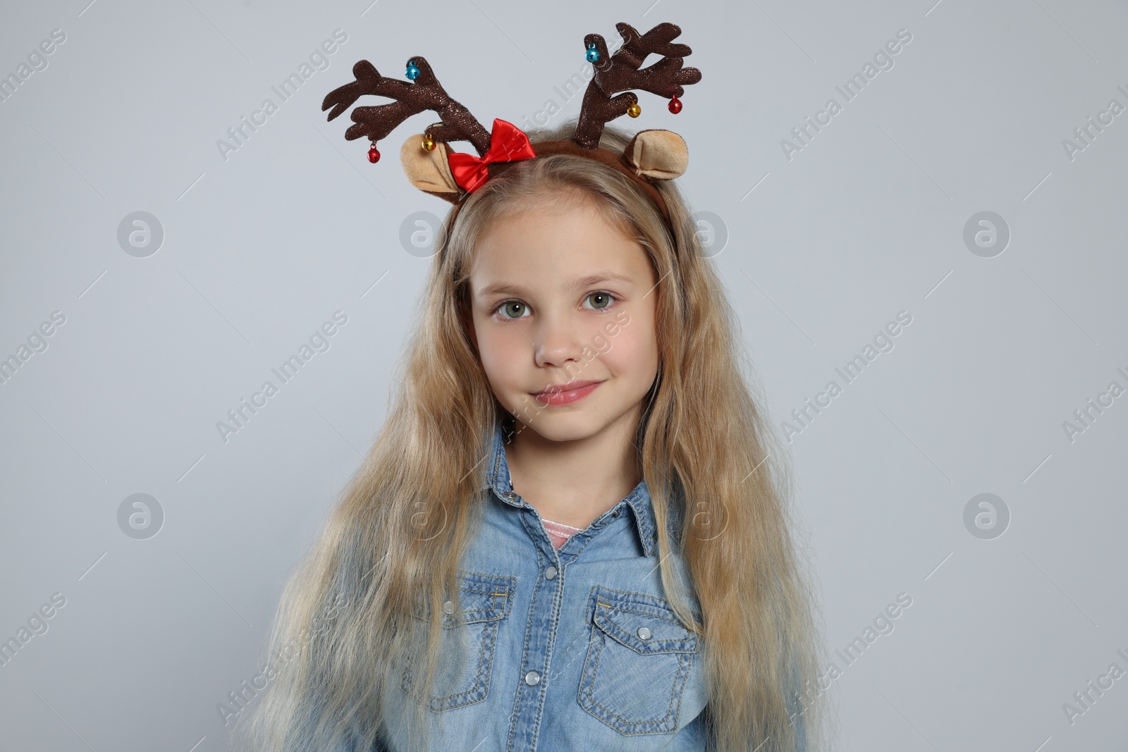 Photo of Girl with decorative Christmas headband on light grey background