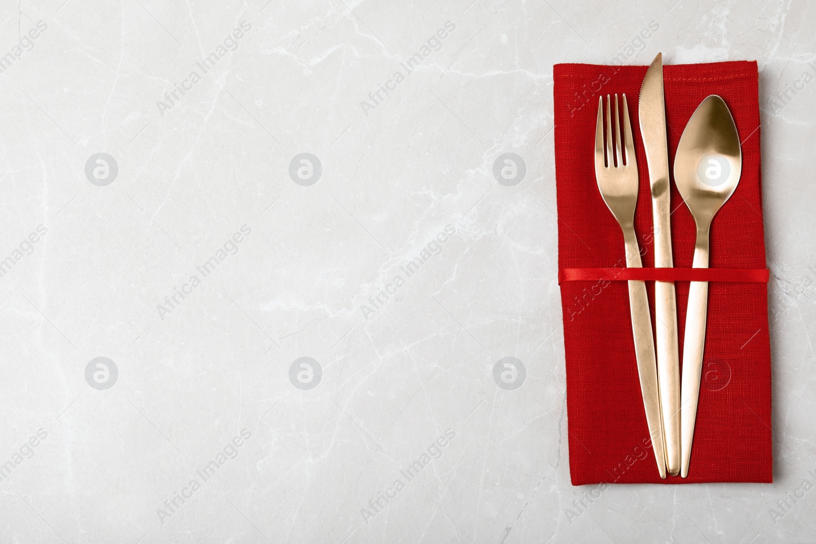 Photo of Napkin with golden cutlery on table, top view. Space for text