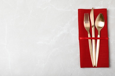 Photo of Napkin with golden cutlery on table, top view. Space for text