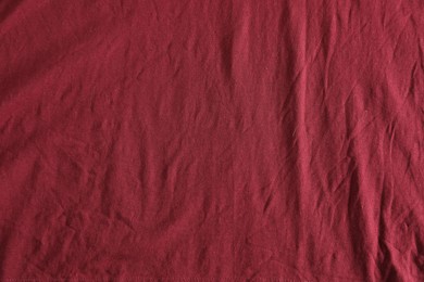 Photo of Crumpled dark red fabric as background, top view