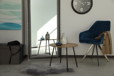 Photo of Room with wooden table and blue armchair. Stylish interior