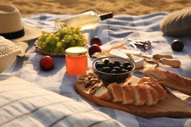Photo of Different tasty snacks on picnic blanket outdoors