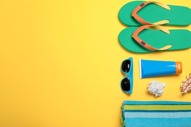 Stylish flip flops and beach objects on yellow background, flat lay. Space for text