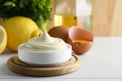 Photo of Fresh mayonnaise sauce in bowl on white wooden table, closeup. Space for text