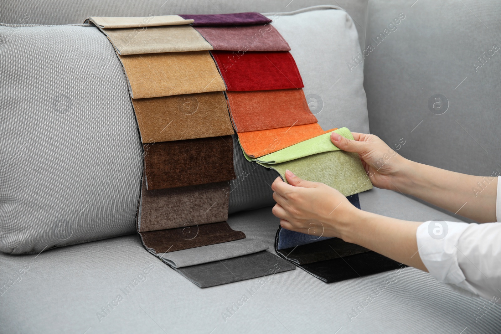 Photo of Woman choosing fabric among colorful samples on grey sofa, closeup