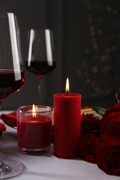 Photo of Place setting with roses and candles on white table, closeup. Romantic dinner