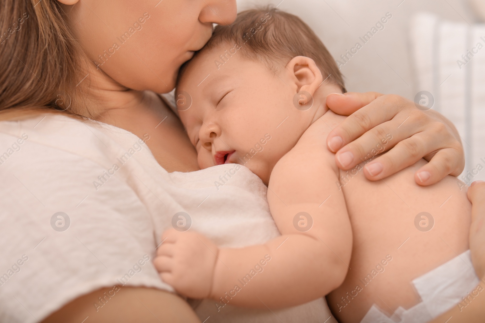 Photo of Mother kissing her cute newborn baby indoors