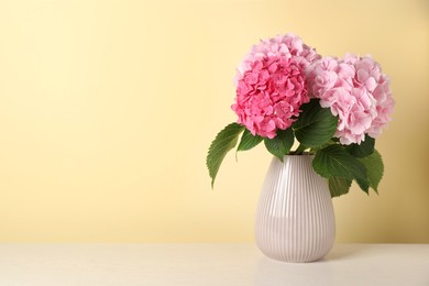 Photo of Bouquet with beautiful hortensia flowers on white wooden table against yellow background. Space for text