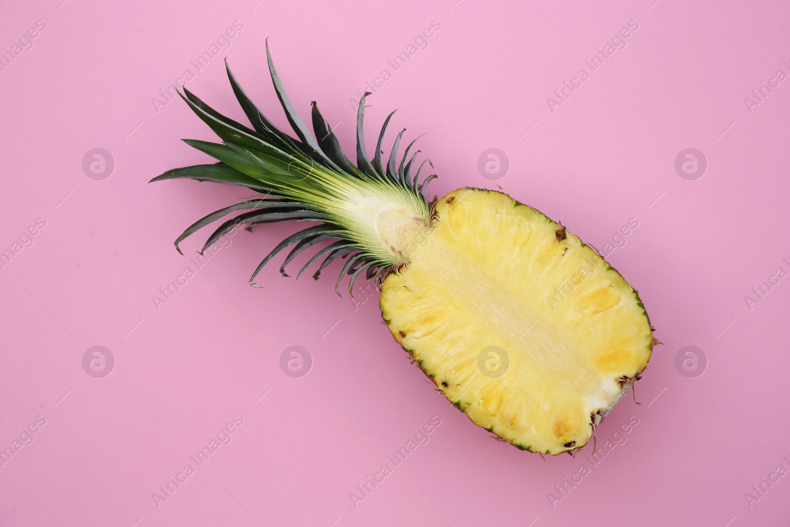 Photo of Half of ripe pineapple on pink background, top view
