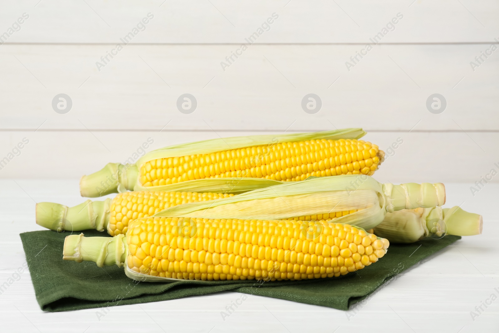 Photo of Tasty fresh corn cobs on white wooden table