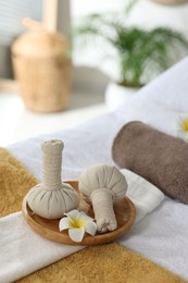 Photo of Herbal bags, flowers and towels on massage table in spa