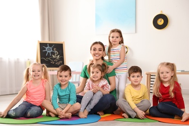 Photo of Kindergarten teacher with group of children in playroom. Indoor activity