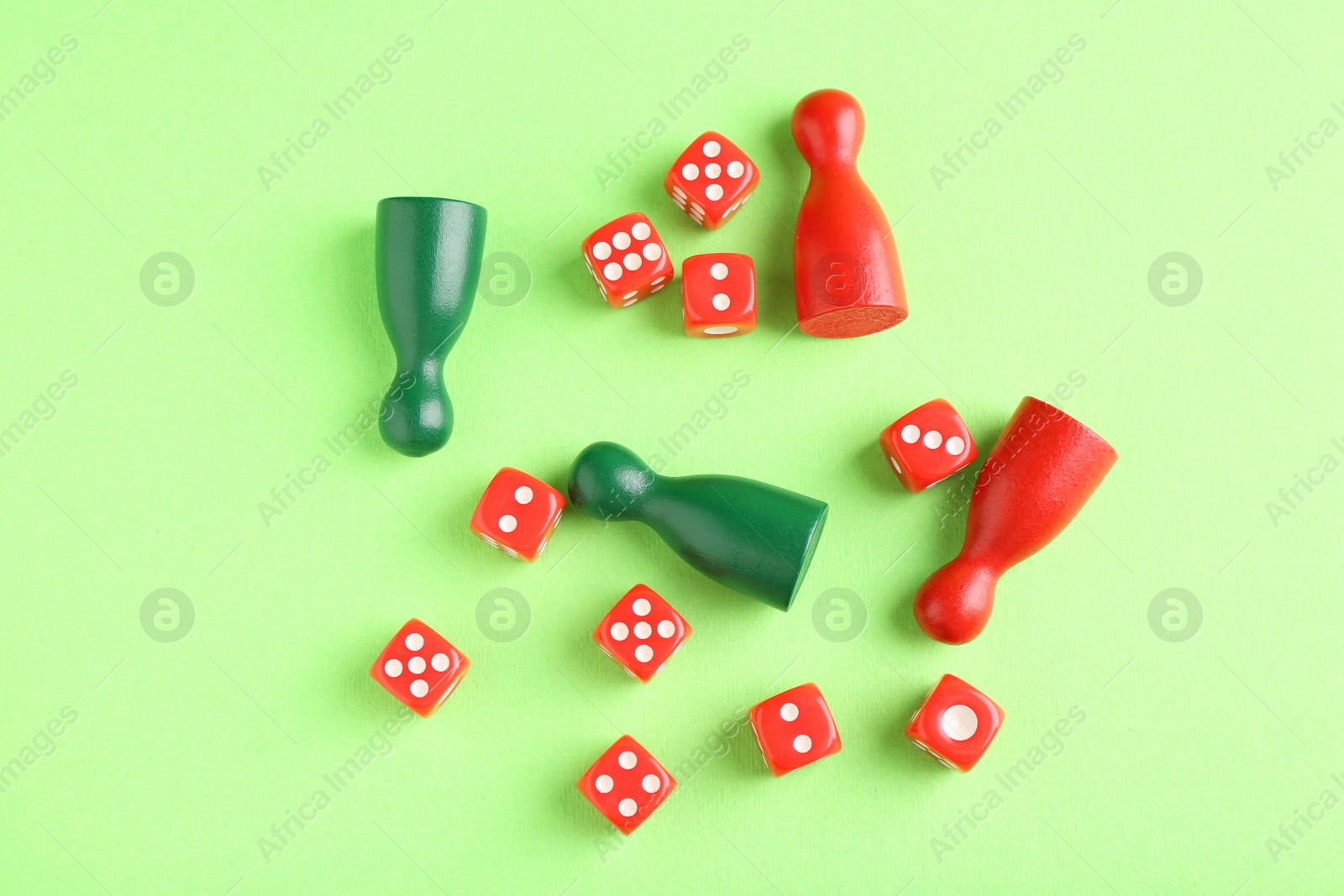 Photo of Many red dices and color game pieces on green background, flat lay