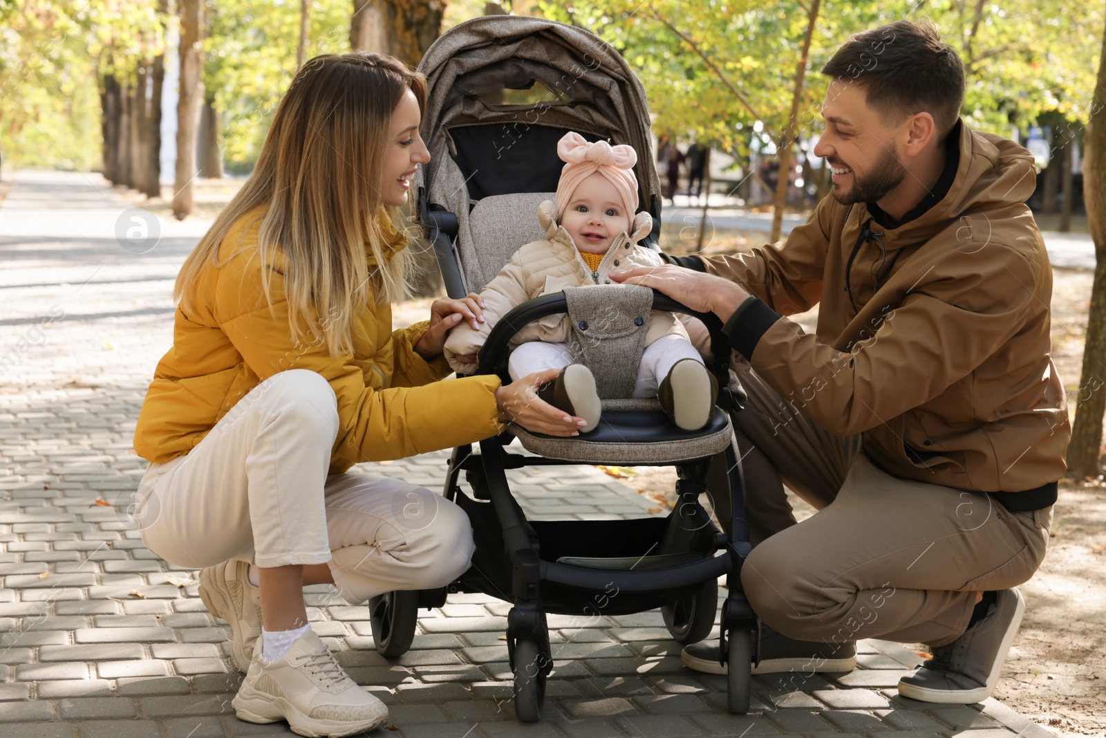 Photo of Happy parents with their baby in stroller at park on sunny day