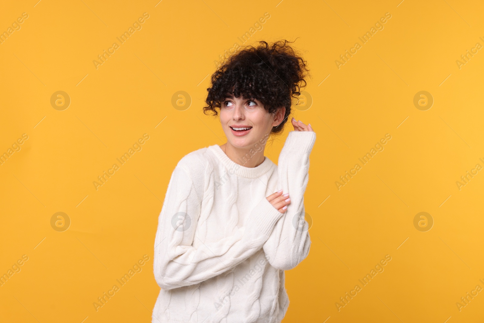 Photo of Happy young woman in stylish white sweater on yellow background