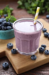 Photo of Glass of blueberry smoothie with fresh berries on wooden table, closeup