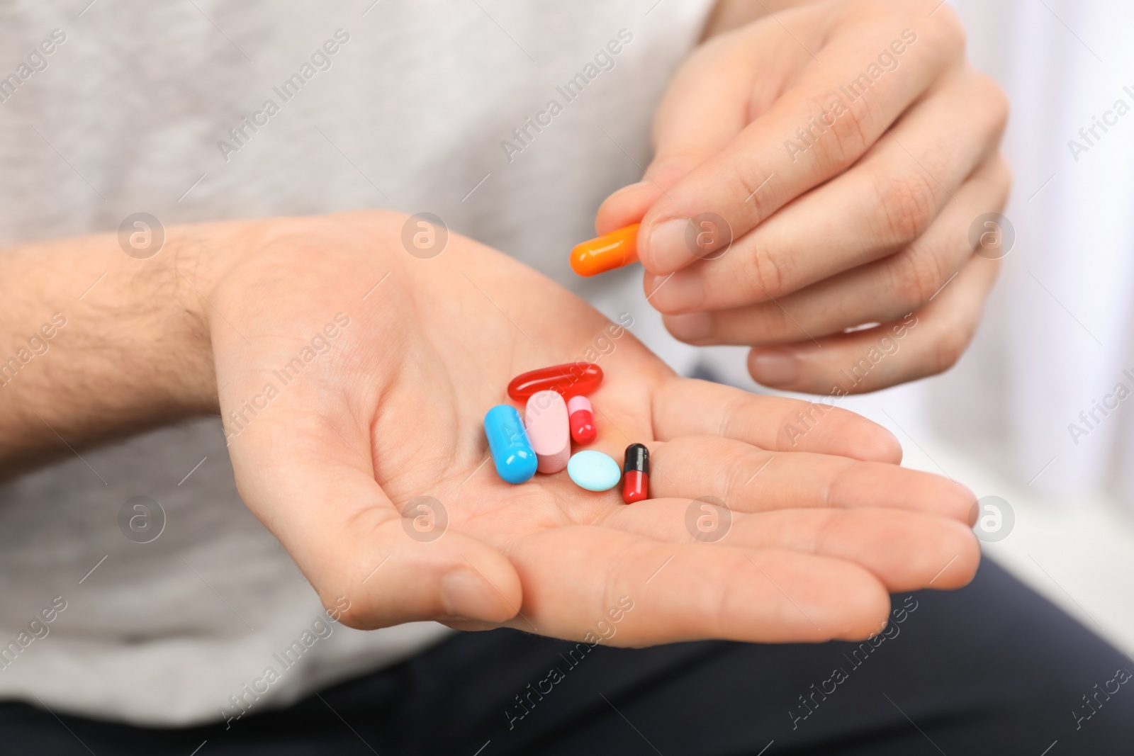 Photo of Young man holding different pills, closeup