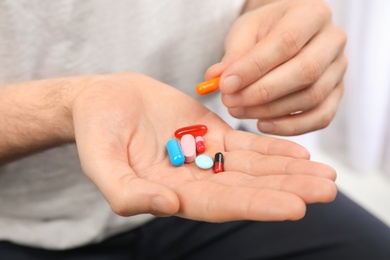 Young man holding different pills, closeup