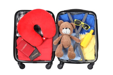 Photo of Soft travel pillow, toy bear, passports and other items in open suitcase isolated on white, top view