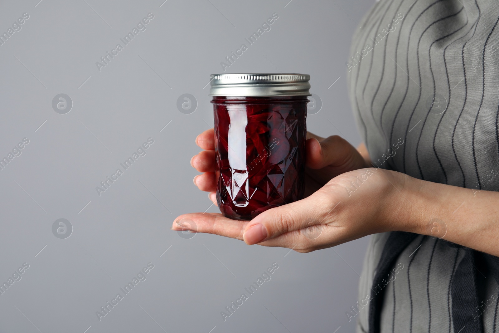 Photo of Woman holding glass jar with pickled beets, closeup