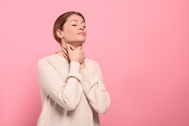 Photo of Woman suffering from sore throat on pink background. Space for text