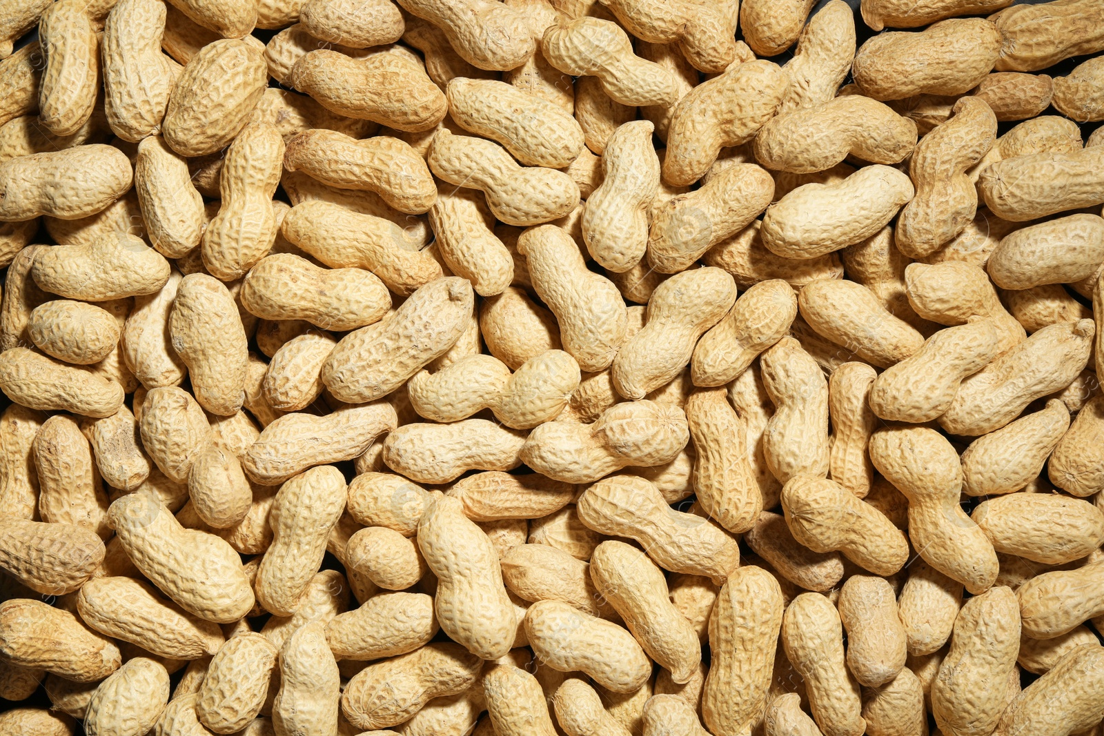 Photo of Many fresh unpeeled peanuts as background, top view