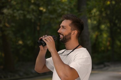 Handsome man with binoculars spending time in nature reserve