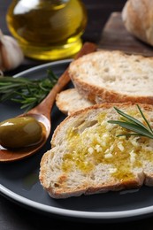 Tasty bruschettas with oil and rosemary on plate, closeup