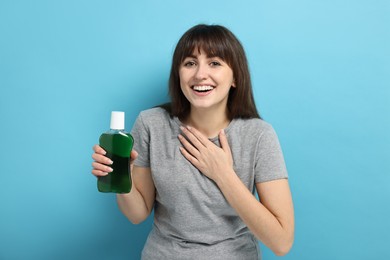 Photo of Young woman with mouthwash on light blue background